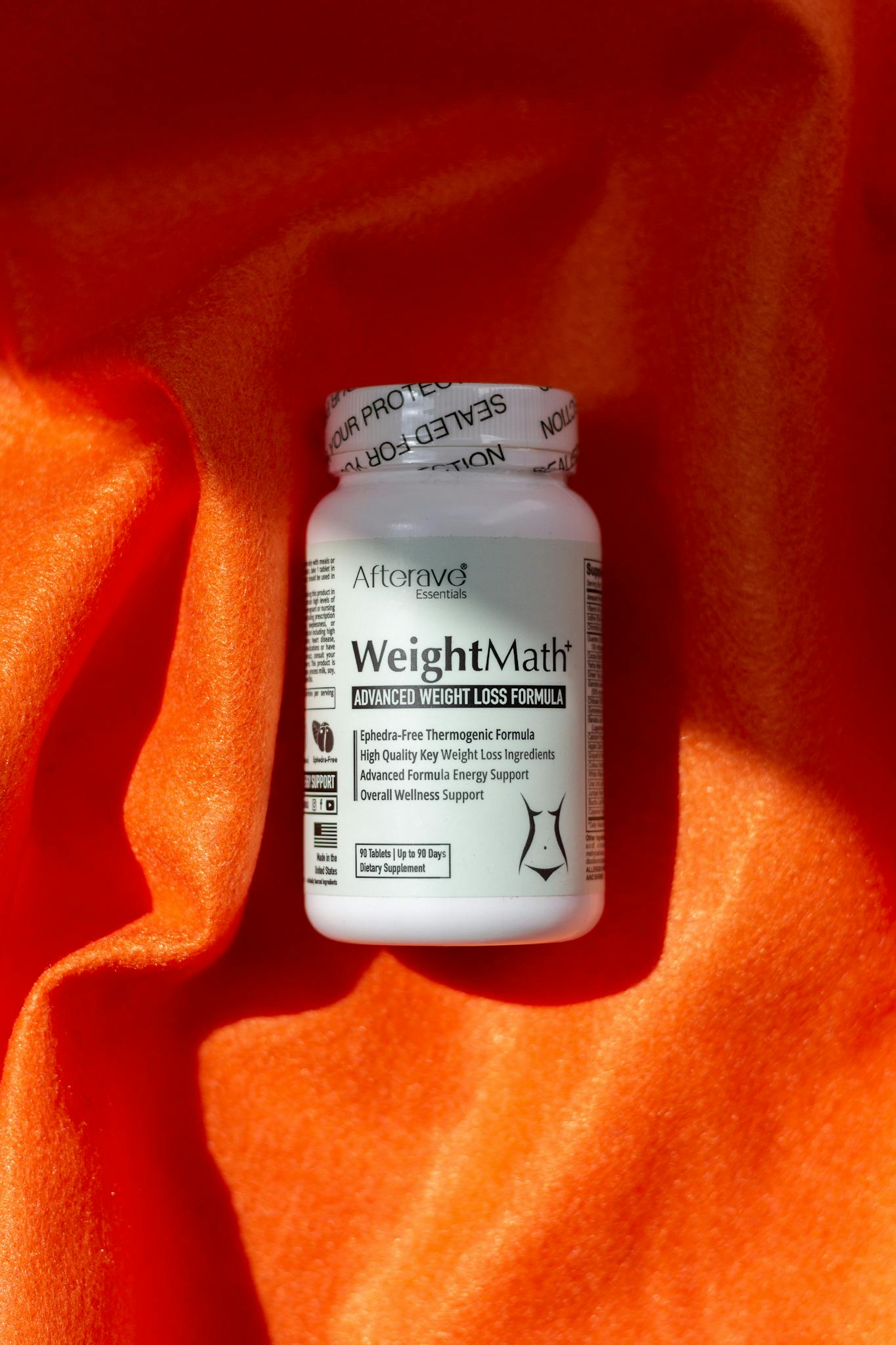 Weight loss supplement bottle on vibrant orange fabric, promoting diet and metabolism boost.